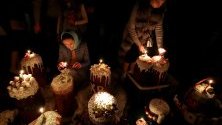 Православни вярващи палят свещи в очакване на благословията на великденските сладкиши, на православна църква по време на Великденска служба в Бишкек, Киргизстан.