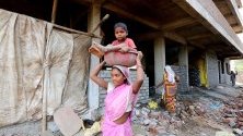 Индийка носи детето си на главата си близо до строителна площадка по повод Международния ден на труда или майския ден в Бхопал, Индия.
