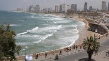 Туристите се разхождат по крайбрежната алея Яфа, заобиколена от силуета на Тел Авив, Израел. Според общината 10 000 до 20 000 туристи се очаква да посетят града за конкурса за песен Евровизия, който се провежда от 14 до 18 май 2019 г.