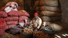 Работник сортира картофи на пазара в Карачи, Пакистан.