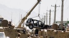 Войниците на НАТО преместват разрушено бронирано превозно средство от американски конвой след взрив. В Кабул избухна кола бомба, която уби и рани поне седем души.