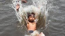 Индийско момче скача в канализационния канал на града, за да се охлади в Ню Делхи, Индия. 