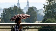 Жена използва чадър, за да се защити от слънцето, докато ходи в Дрезден, Германия. 