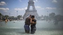 Двойка се охлажда във фонтаните на Трокадеро, срещу Айфеловата кула, по време на горещини в Париж, Франция.