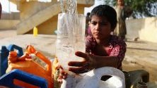 Местни жители изчакват да напълнят кутиите си с питейна вода в Карачи, Пакистан. Недостиг на вода засяга различни части на града от началото на лятото.
