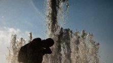 Човек се охлажда с вода във фонтан в парк Лустгартен в Берлин, Германия.
