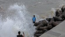 Индиец  позира за снимка по време на прилив в Арабско море на крайбрежната алея в Marine Drive в Момбай, Индия.
