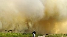 Мъж се вози с мотоциклета си покрай пожар в  провинция Южна Суматра, Индонезия.