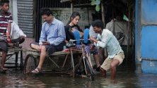 Индиец управлява рикшата си, пълна с пътници, по наводнените улици на село Раджпур, в Западен Бенгал, южно от Калкута. Повечето къщи в Раджпур се намират под вода.