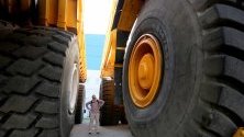 Посетител между гумите на два 450-тонни камиони на беларуската компания BelAZ, предназначени за минодобив.