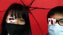 Ученици от Хонконг са покрили очите си очите си в солидарност с жена, пострадала в окото по време на сблъсъци с полицията.
