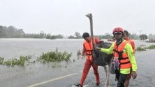 Спасител помага на щраус от наводнена територия в северната провинция Ясотон, Тайланд. Наводненията, причинени от тропическата буря Подул, засегнаха няколко провинции и стотици хиляди хора.