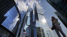 Хора  минават покрай кулите на бизнес центъра Москва Сити в Москва, Русия.