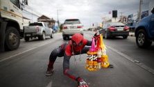 Уличен търговец в Тайланд продава стоката си в костюм на Спайдърмен. 