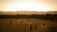 Деца играят футбол в поле край селото им в покрайнините на Кабул, Афганистан.