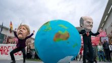 Климатични активисти протестират с маски на канцлера Ангела Меркел и финансовия министър на Германия Олаф Шолц пред канцлерството в Берлин.