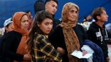 Семейство мигранти чака на пристанището в Пирея, Гърция, след пристигането си с ферибот от бежанския лагер на остров Лесбос. Те ще бъдат преразпределени в различни центрове из страната заради препълването на лагера.