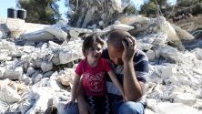 Палестинец и детето му седят край разрушена от израелските части постройка в Биет Омар, на Западния бряг. Израелската армия регулярно разрушава палестински сгради в района поради липса на разрешение за строеж.