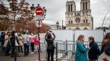Туристи снимат катедралата Нотр Дам по време на възстановяването й - шест месеца след опустошителния пожар.