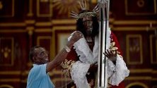 Мъж пали свещ пред статуя на Черния Исус от Портобело (Cristo Negro de Portobelo) в едноименния град в Панама.