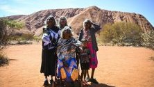 Аборигени, собственици на земята в района, позират пред скалния масив Улуру в Австралия в деня, в който вече е забранено на туристите да се катерят по него.