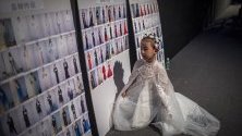 Младо дете - модел разглежда табло със снимки на други модели и облеклото им в бекстейджа преди дефиле по време на Седмицата на модата в Пекин, Китай.