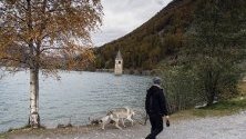 Мъж се разхожда край камбанария на бивша църква в село напълно потопено в язовир през 1950 година, в Решензее (Lago di Resia) край Граун в Тирол, Италия. 