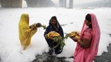 Индийски вярващи изпълняват ритуали в замърсената река Ямуна, покрита с токсична пяна от близкия завод, по време на фестивала Чат Пуджа в Ню Делхи, Индия. 