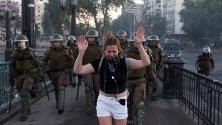 Протестите в Чили не стихват - демонстрантка плаче, ескортирана от полицаи по време на протест в Сантяго.
