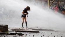 Полицията облива с водни струи демонстрантка по време на поредния ден на протести в Сантяго, Чили.
