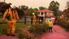 Къщи, покрити с химическо вещество, възпиращо огъня и хвърлено от хеликоптер, Южен Турамура край Сидни, Австралия. Най-малко 60 пожара горят в Нов Южен 