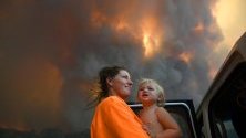 Майка с дъщеря се евакуират от горските пожари край Нана Глен, Нов Южен Уелс, Австралия- Над 50 пожара горят в региона, като близо половината не са овладяни.