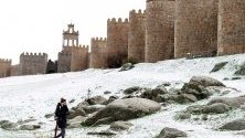 Жена минава край градските стени на Авила след снеговалеж, Централна Испания. Ниско налягане преминава над страната със снеговалежи, дъждове, ветрове и спадане на градусите.