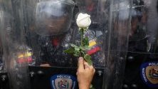Протестиращ подава бяла роза на спецчастите по време на студентски протест пред Университета на Венецуела в Каракас.