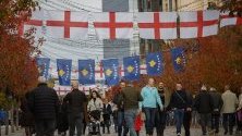 Пешеходци минават под английски и косовски знамена, окачени за мача от Евро 2020 между Косово и Англия в Прищина.