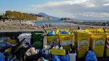 Хора почистват пластмасови боклуци и отломки след бурите, донесени от вълните на брега край Неапол. 