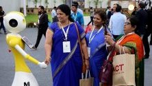 Индийки се ръкуват с робот по време на 22-рото технологично изложение в Бангалор, Индия.