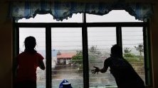 Филипинци гледат през прозорец на евакуационен център силните ветрове, докарани от тайфуна Камури.