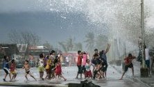 Деца си играят на силните вълни при дига в град Легазпи, Филипините, предизвикани от тайфуна Камури.