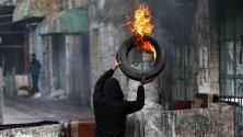 Палестинец подготвя горяща барикада по време на сблъсъци с израелските части в Хеброн, Западен бряг. Палестинците протестират срещу плана на Израел да разруши пазар за плодове и зеленчуци в стария град, за да изгражда нов кибуц.