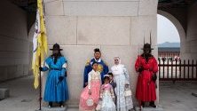Туристи, облечени в традиционно южнокорейско облекло ханбок, позират за снимка по време на посещение в двореца Кьонбокун в Сеул.
