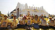 Тайландци държат снимки на крал Маха Вачиралонгкорн и кралица Сутида докато се състои церемонията в чест на една година от коронясването му в двореца в Банкок.