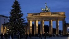 Осветената Бранденбургска врата в Берлин с коледна елха пред нея.