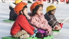 Деца се пързалят на шейни в градски парк в град Бусан, Южна Корея.