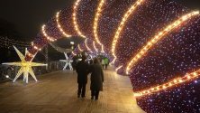 Разхождащи се по украсен за Коледа мост пред катедралата &quot;Христос Спасител&quot; в Москва.