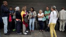 Хора чакат на опашка пред магазин, който приема петро като разплащателна единица, в Каракас, Венецуела. Парите бяха раздадени от президента Николас Мадуро като коледен бонус.