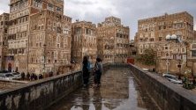 Йеменки минават край исторически сгради след проливни дъждове в стария квартал на Сана.