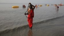 Монах взима баня на брега на Бенгалския залив по време на Ganga Sagar Mela на Остров Сагар, Индия. Ganga Sagar Mela е годишно събиране на вярващи индуси, които извършват ритуални къпания за прочистване на душите в река Ганг.