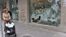 Ливанци минават край разрушена витрина на Банката на Бейрут след антиправителствени протести в града.