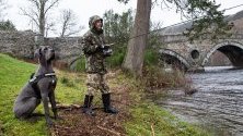 Рибар и неговият дог ловят риба в река Тей в Шотландия по време на откриването на сезона за улов на пъстърва. 